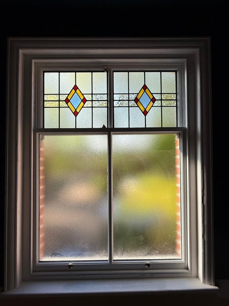 A sash window with a top panel of stained glass restored in Didsbury by Sash Window Solutions